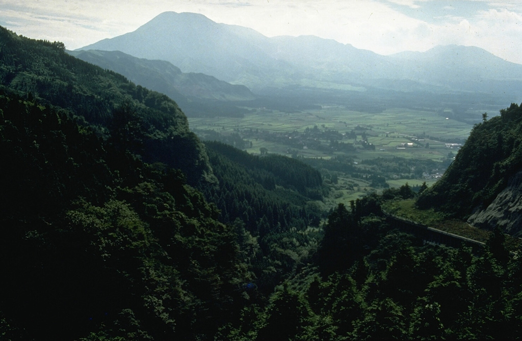The 24-km-wide Aso caldera formed during four major Pleistocene explosive eruptions. These produced voluminous pyroclastic flows that swept over much of Kyushu. A group of 17 cones was constructed in the central part of the caldera, seen here from the ENE caldera rim. The Nakadake cone is one of Japan's most active volcanoes with recorded eruptions dating back to 553 CE. Photo by Norm Banks, 1981 (U.S. Geological Survey).