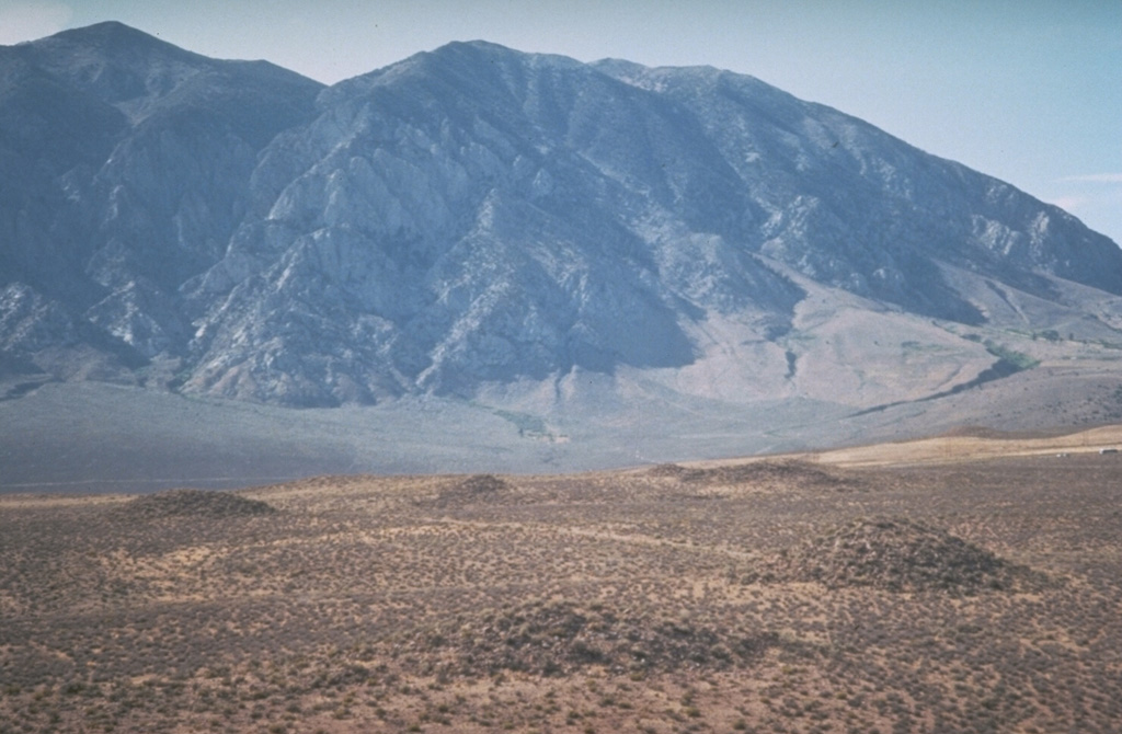 The light-colored area in the foreground is the surface of the Bishop Tuff,  500 cu km of airfall-pumice and pyroclastic-flow deposits related to the formation of the Long Valley caldera about 760,000 years ago.  The low mounds formed as a result of degassing of the deposit while it cooled. Photo by Larry Mastin, 1992 (U.S. Geological Survey).