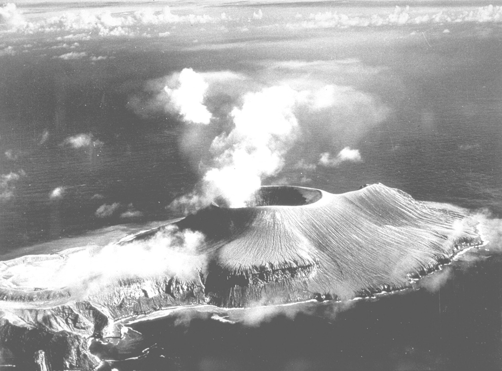 This aerial view from the west shows the new Volcán Bárcena summit crater producing a plume. The 700-m-wide crater  had grown to a height of about 380 m in the first two weeks of the eruption. At the time of this 20 September 1952 photo, taken about seven weeks after the start of the eruption, the first of two lava domes had emerged in the summit crater. Extrusion of a lava flow that formed a delta on the far SE side of the island had not yet begun. Photo by U.S. Navy, 1952 (courtesy of Sherman Neuschel, U.S. Geological Survey).