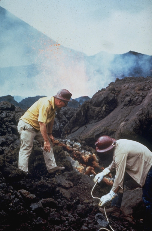 Scientists sample fumaroles near the flank vent at Cerro Negro in November 1968.  Incandescent spatter is ejected from the vent in the background behind volcanologist Dick Stoiber (left), who led many expeditions from Dartmouth College to Central American volcanoes.  This fumarole was a source of tenorite (CuO) and other minerals. Photo by Dick Stoiber, 1968 (Dartmouth College).