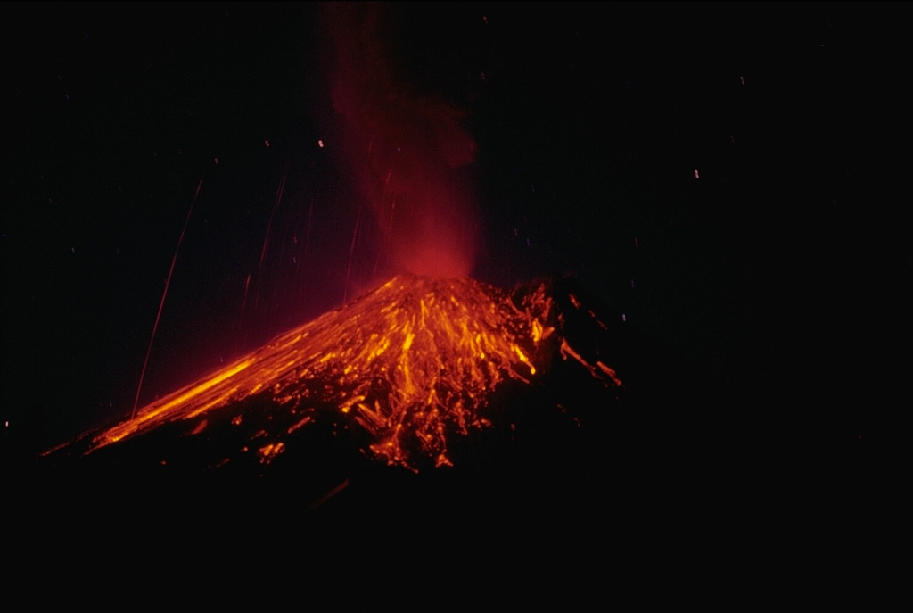 A nighttime time-exposure photo of Arenal on 3 April 1990 shows the paths of incandescent blocks that landed on the upper flanks and traveled downhill. Near-constant lava effusion, accompanied by periods of heightened explosive activity, has occurred since a large explosive eruption in 1968. Photo by William Melson, 1990 (Smithsonian Institution).