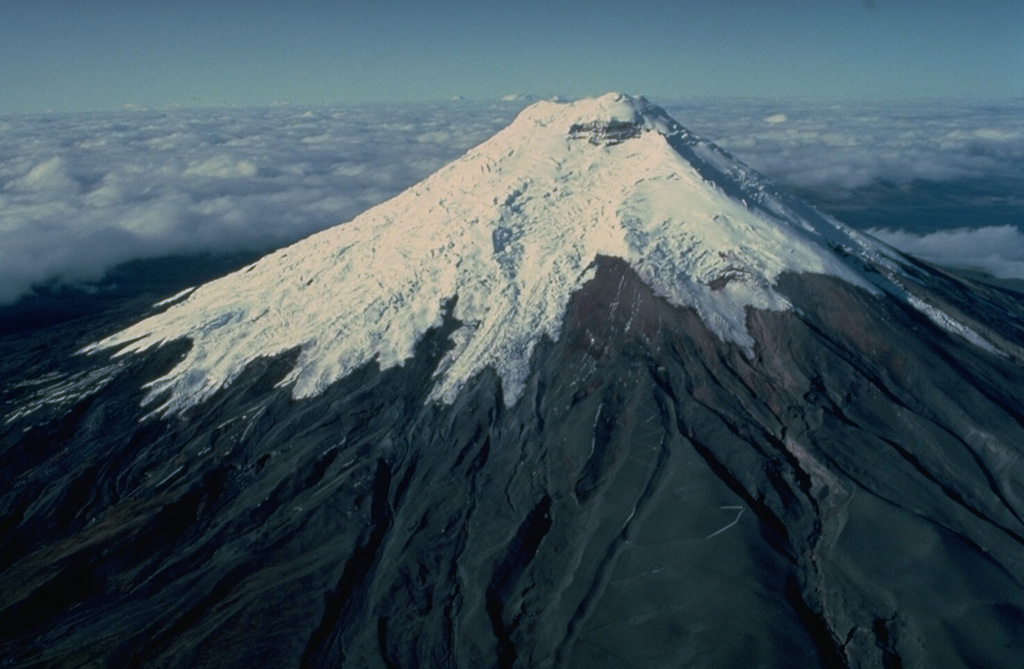 The symmetrical, glacier-clad Cotopaxi stratovolcano is Ecuador's best known volcano and one of its most active.  The steep-sided cone, seen here in an aerial view from the north, is capped by nested summit craters 650 x 800 m in diameter.   Lahars accompanying explosive eruptions of Cotopaxi have frequently devastated adjacent valleys.  In 1877, during one of the largest historical eruptions, pyroclastic flows descended all sides of the volcano and lahars traveled more than 200 km into the Pacific Ocean and the western Amazon basin.   Copyrighted photo by Katia and Maurice Krafft, 1983.