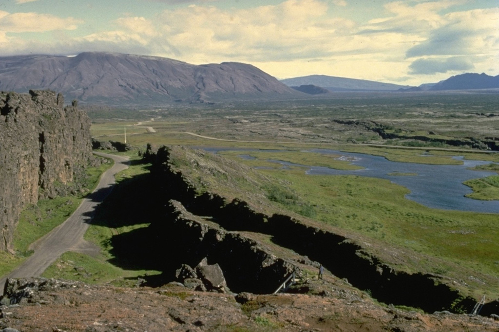 The Hengill volcanic system, mostly located SW of Thingvallavatn lake, consists of a series of NE-SW-trending fissure vents, crater rows, and small shield volcanoes occupying a strongly faulted graben.  This view looks NE from the margin of a graben containing Hengill lava at Thingvellir, the site of Iceland's old parliament.  The latest eruption of the Hengill volcanic system was radiocarbon dated at about 1900 years before present.  Geothermally heated greenhouses, hot springs, and geysers are found at Hveragerdi.   Copyrighted photo by Katia and Maurice Krafft.
