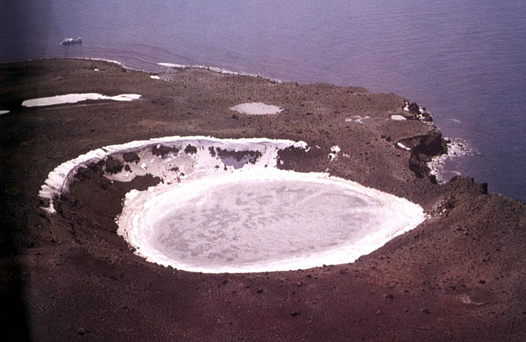 The ice-filled crater of Petrel maar is here seen from the southwest; this approximately 300-m-wide crater formed in a phreatomagmatic eruption about 1905 CE. Petrel maar and Deacon Peak are the two main vents identified on Penguin Island, and represent the youngest activity.   Photo by Oscar González-Ferrán (University of Chile).