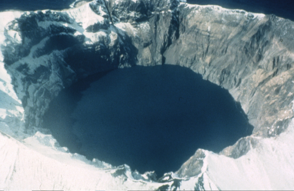 A 750-m-wide crater filled with a lake truncates the summit of Kasatochi. Crater walls rise to a maximum height of 314 m above the lake surface, which is less than 60 m above sea level in this 1961 photo. The volcano is located at the northern end of a shallow submarine ridge trending perpendicular to the Aleutian arc and occupies an island volcano 2.7 x 3.3 km wide.  Photo by Dan Rogers, 1961 (courtesy of Alaska Volcano Observatory, U.S. Geological Survey).