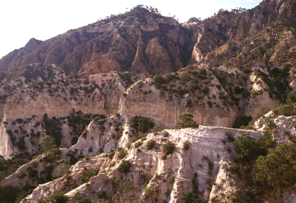 The pyroclastic surge deposits in the foreground are exposed in front of Cerro Pinto lava dome. The dome has a glassy and pumiceous outer layer partly overlain by pyroclastic surge deposits and blocks of local bedrock. Photo by Gerardo Carrasco-Núñez, 2002 (Universidad Nacional Autónoma de México).