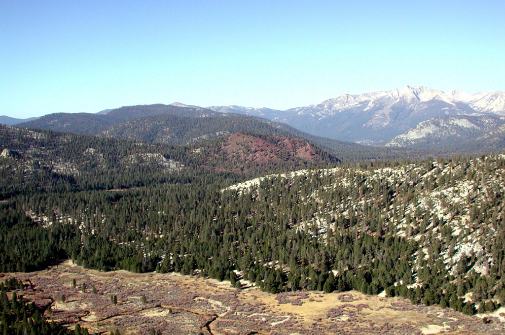 Groundhog cinder cone (center) is seen from the NE with Tunnel Meadow in the foreground.  Peaks of the Great Western Divide across Kern Canyon in Sequoia National Park are visible on the right horizon.  Groundhog cone is the youngest of the group of cinder cones forming the Golden Trout Creek volcanic field in the Golden Trout Wilderness Area.  This nomenclature derives from the renowned Golden trout, which is a sub-species of rainbow trout and has been designated as the official state fish of California.   Photo by Rick Howard, 2002 (courtesy of Del Hubbs, U S Forest Service).