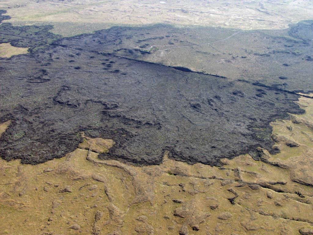 The dramatic Kings Bowl rift cutting diagonally across the top of the photo produced a small 6-sq-km lava field about 2250 years ago immediately north of the much larger Wapi lava field.  Kings Bowl itself is the small elongated crater on the right-center side of the rift in this photo; it formed during a phreatic explosion that deposited lighter-colored tephra to the east (upper right).  The massive Wapi lava field, located out of view south (right) of Kings Bowl, covers an area of about 325 km2 and originated from Pillar Butte, a small shield volcano.   Photo by Susan Sakimoto (NASA, courtesy of Scott Hughes, Idaho State University).