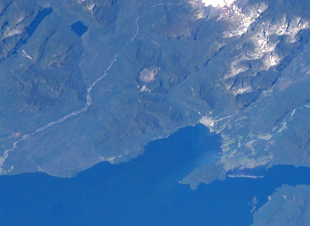 The small circular feature just above the center of this NASA International Space Station image (with north to the upper left) is Chaitén caldera.  It is located 10 km NE of the town of Chaitén, the light-colored area along on the Gulf of Corcovado below and to the right of the caldera.  This small, glacier-free, 3.5-km-wide caldera is of Pleistocene age, but has a rhyolitic Holocene lava dome.   NASA International Space Station image ISS006-E-42131, 2003 (http://eol.jsc.nasa.gov/).
