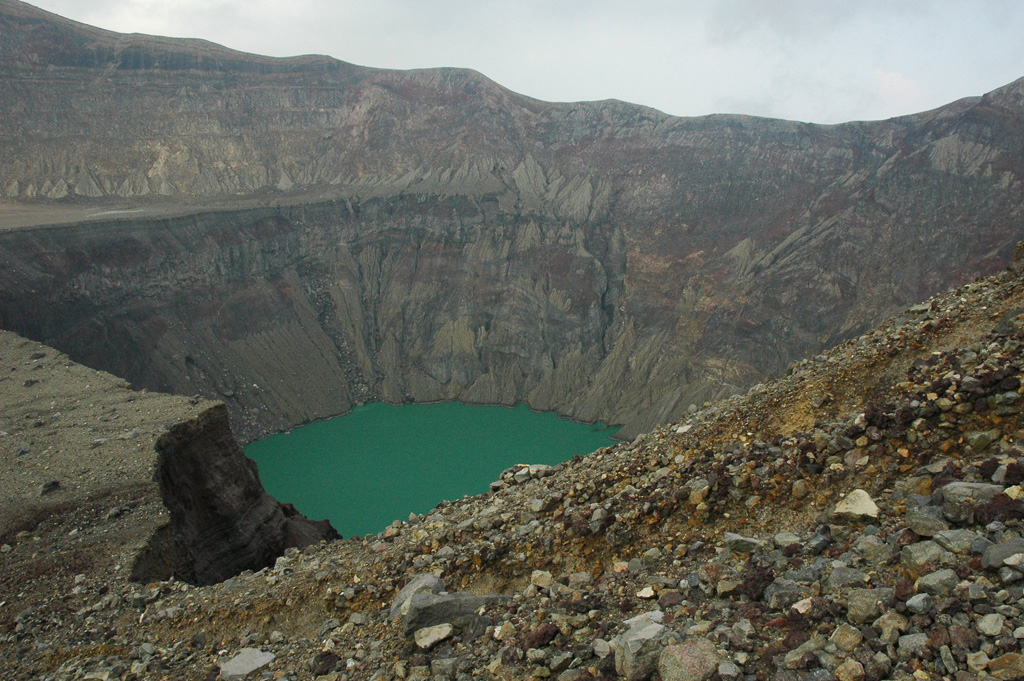 The Santa Ana crater lake is in the smallest and deepest of several nested craters across the summit that formed during successive explosive events, seen here in 2011 from the western side on the terrace level. The acid sulfate-chloride lake has a pH around 1, with an associated subsurface hydrothermal system that releases gases into the water. Photo by Lis Gallant, 2011.