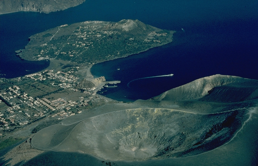 The peninsula of Vulcanello (upper left), at the northern end of the island of Vulcano, is the latest of a series of north-migrating eruptive centers on Vulcano.  Its growth began in 183 BCE, when submarine eruptions formed an island.  Eruptions eventually formed three cones up to 123-m high surrounded by lava flows that joined Vulcanello to the main island.  The crater in the foreground is Fossa, the source of most historical eruptions of Vulcano. Copyrighted photo by Katia and Maurice Krafft, 1982.