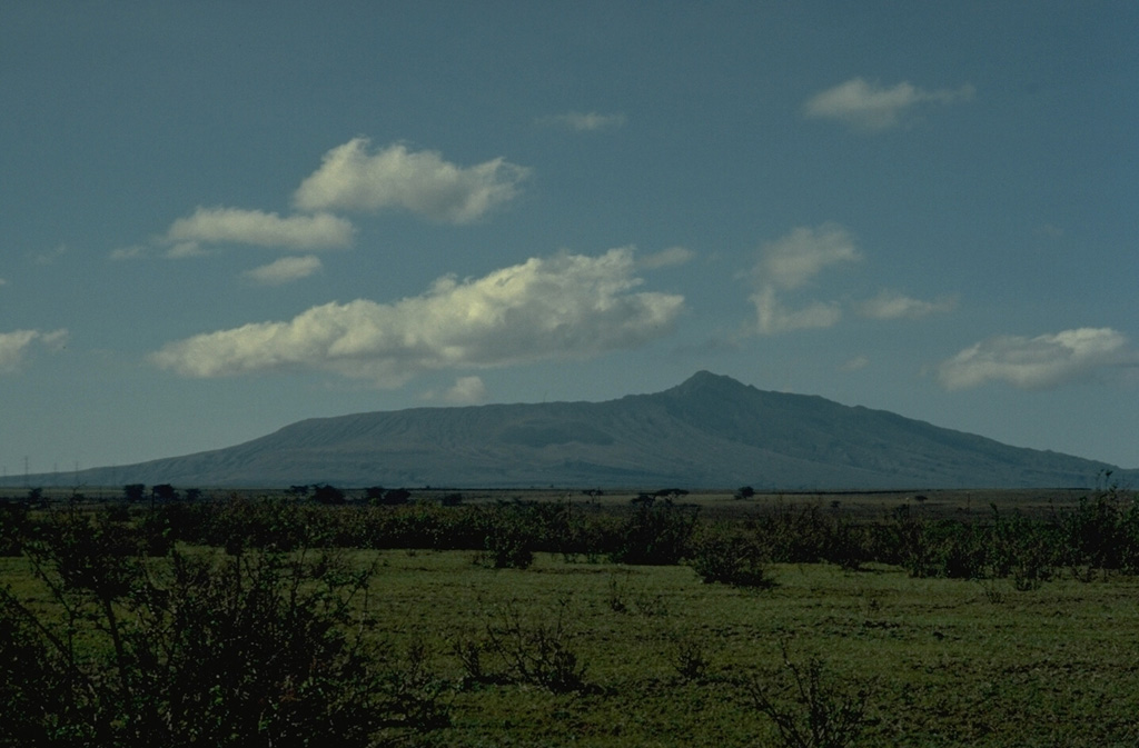 The central cone of Longonot volcano was constructed within a large, topographically indistinct caldera.  The summit of Longonot, seen here from the north, is the west rim of a 1.8-km-wide summit caldera.  Late-stage lava flows were erupted on the northern and SW flanks.  Copyrighted photo by Katia and Maurice Krafft, 1976.