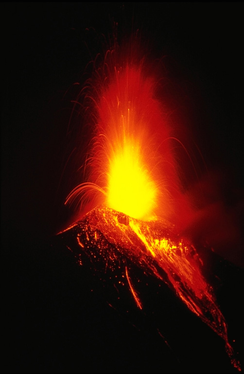 Strombolian eruptions the night of 20 November 1985 ejected incandescent bombs that fell back around the crater and tumbled down the upper flanks. Vigorous Strombolian eruptions resulted in the accumulation of large amounts of unstable material on the upper flanks that produced incandescent avalanches reaching out to 5 km from the crater. This photo was taken three days after the start of the week-long eruption. Lava flows also effused from the summit crater and traveled down the NW flank. Photo by Wally Johnson, 1985 (Australia Bureau of Mineral Resources).