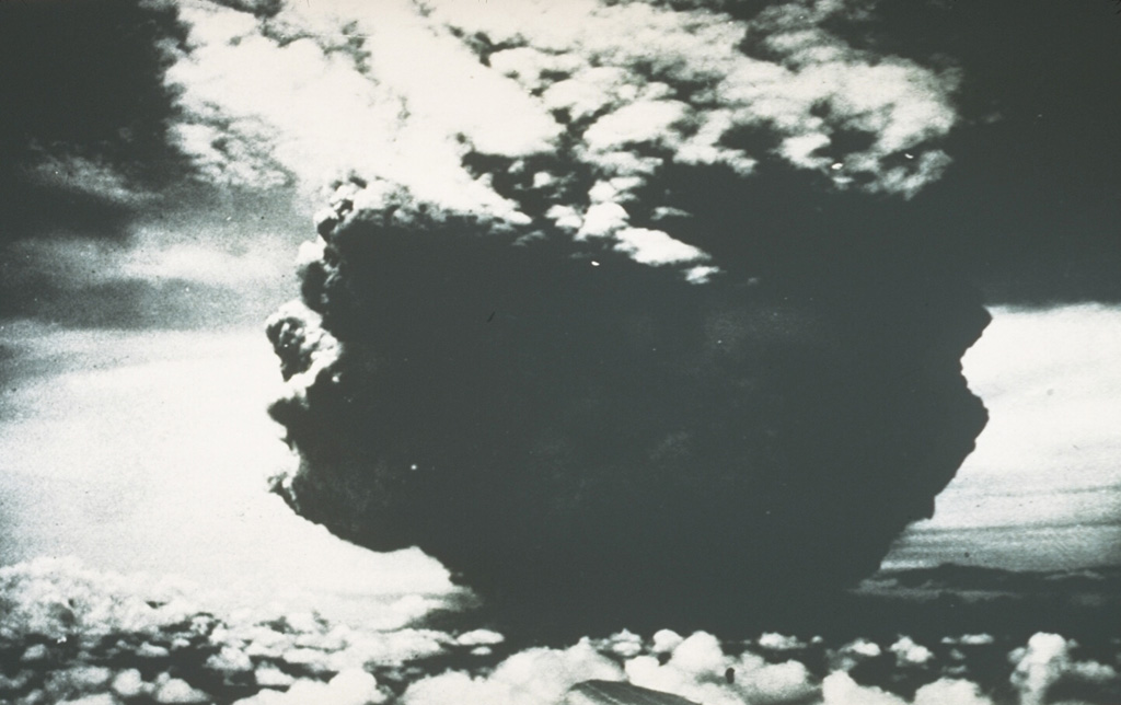 This photograph of the catastrophic eruption of 21 January 1951 was taken by the pilot flying from Port Moresby to Rabaul. From about 40 km NW, the pilot observed this ash plume rising to a height of about 13 km within two minutes. Shortly afterwards, the cloud expanded horizontally away from the volcano as devastating pyroclastic flows and surges swept radially up to 12 km from the crater. Photo by Capt. Jacobson, 1951 (published in Taylor, 1958).