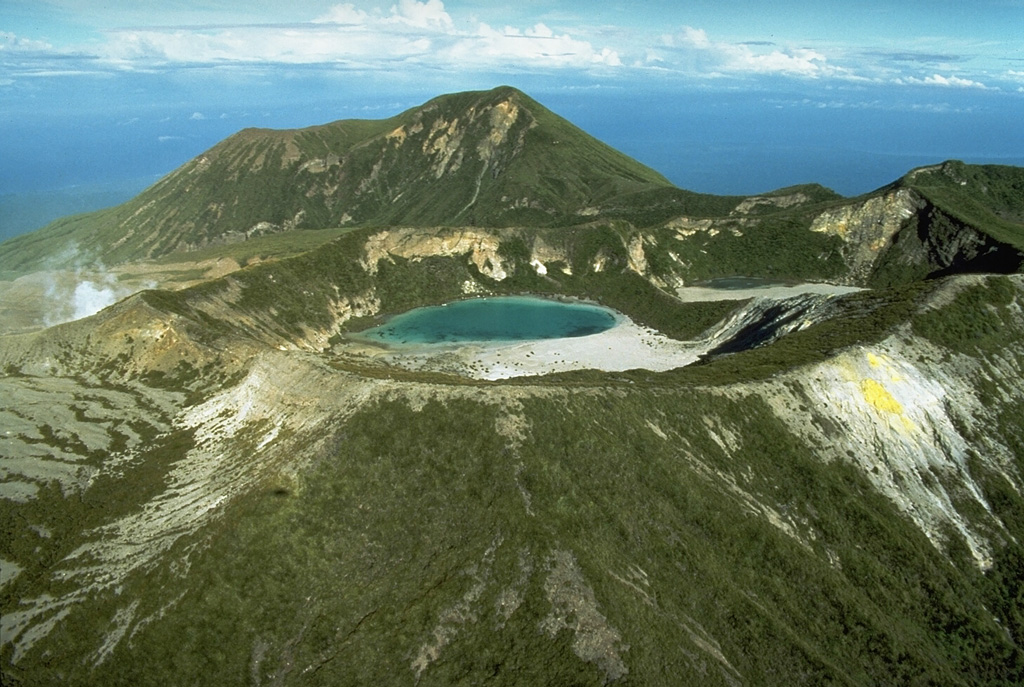 Balbi volcano forms the highest point on Bougainville Island and is part of a large number of coalesced cones and lava domes. Five well-preserved craters occupy a NW-SE-trending ridge N of the summit, which also has a crater. Crater C, containing a small lake, is seen here from the E. A plume from a fumarole field on the W flank of 600-m-wide Crater B is visible to the left. The latest eruption may have been as recent as the mid-19th century. Photo by Wally Johnson, 1987 (Australia Bureau of Mineral Resources).