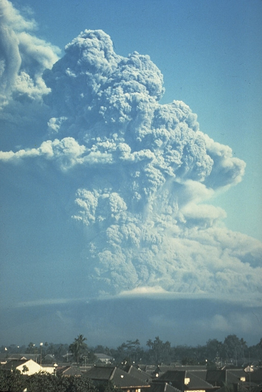 An ash plume from Galunggung volcano towers above the city of Tasikmalaya on 22 July 1982. This was one of a series of strong explosive eruptions between May and October that sometimes deposited ash and pumice on the city, located 17 km ESE of the volcano. Photo by Bob Koyanagi, 1982 (U.S. Geological Survey).