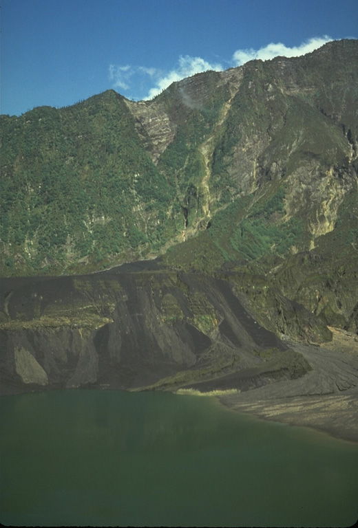 More than three years after the end of the major eruption that began in 1982 the crater had partially been filled by a lake. The dark streaks are lahar deposits that swept into the lake as a result of remobilization of tephra deposits from the eruption. Vegetation has recovered on the steep background wall, which is the SW scarp of the 1-km-deep scar resulting from flank collapse. Photo by Tom Casadevall, 1986 (U.S. Geological Survey).