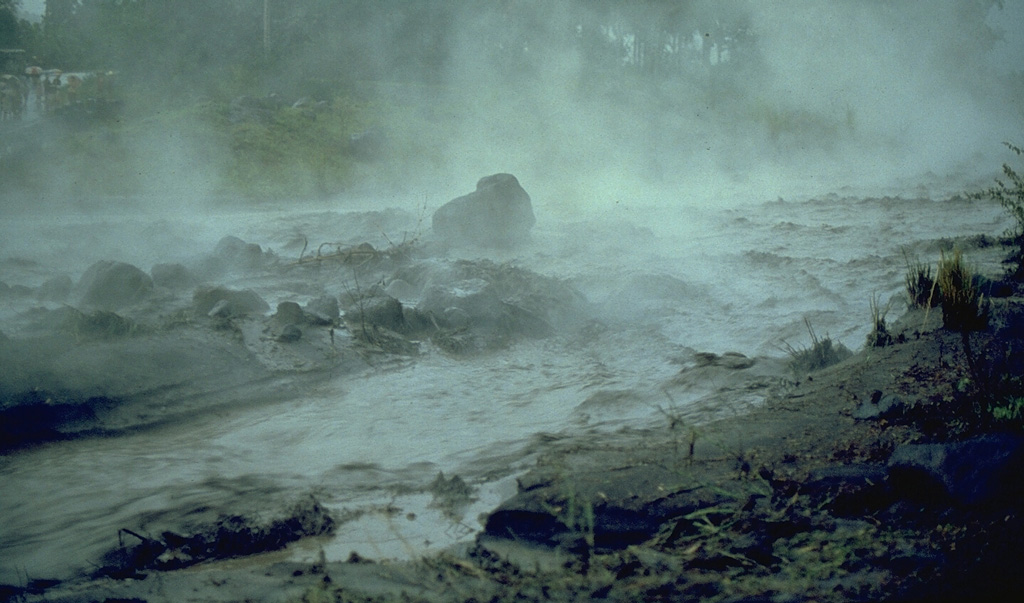 A hot lahar sweeps down a channel on the SW flank of Mayon in the Philippines on 14 September 1984, five days after the onset of an eruption. The water temperature of this lahar was about 80°C. Note the large block in the center of the channel that is being transported by the lahar. Photo by Ernesto Corpuz, 1984 (Philippines Institute of Volcanology and Seismology).