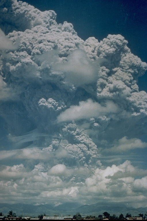 A large Plinian ash plume towers above Pinatubo in the Philippines on 12 June 1991, reaching an altitude of 19 km. This was the first in a series of powerful eruptions that culminated on 15 June with major pyroclastic flows that traveled down all sides of the volcano. Collapse of the summit then created a 2.5-km-wide caldera. This photo was taken from Clark Air Base, about 25 km ENE of Pinatubo. Photo by Karin Jackson, 1991 (U.S. Air Force).