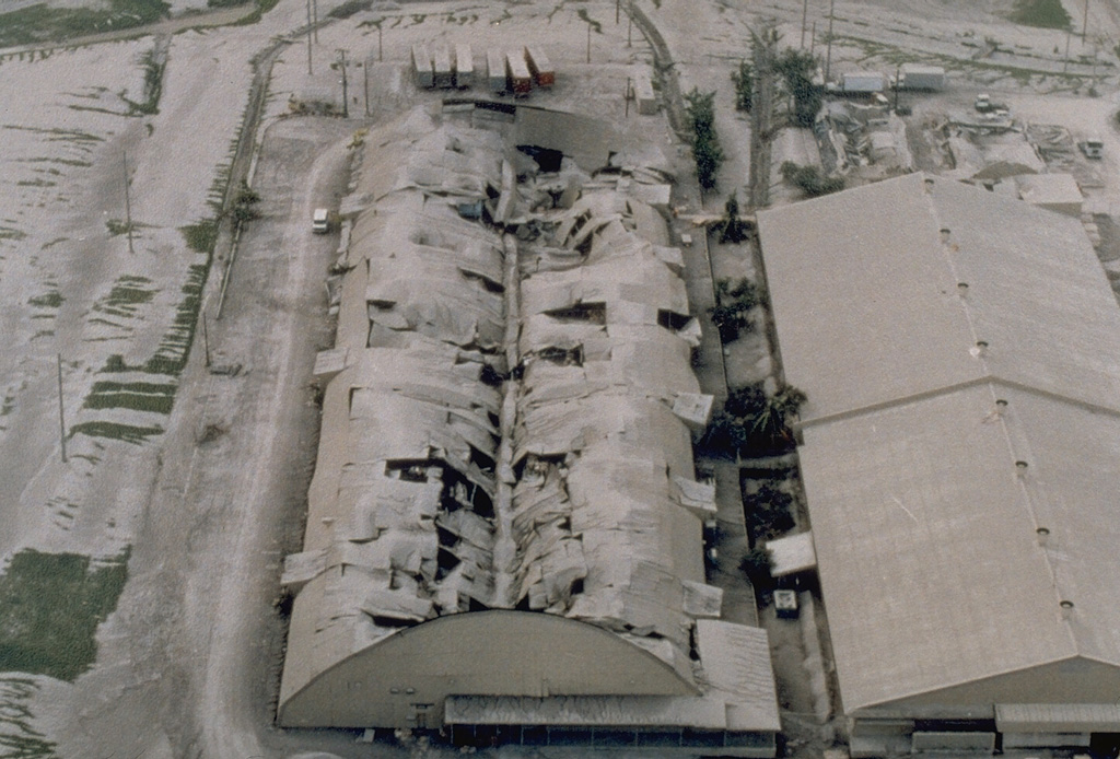 Heavy ashfall from the 15 June 1991 eruption of Pinatubo volcano caused the roof of this warehouse at Clark Air Base to collapse. The base had been evacuated prior to the major explosion on the 15th. Photo by R. Batalon, 1991 (U.S. Air Force).