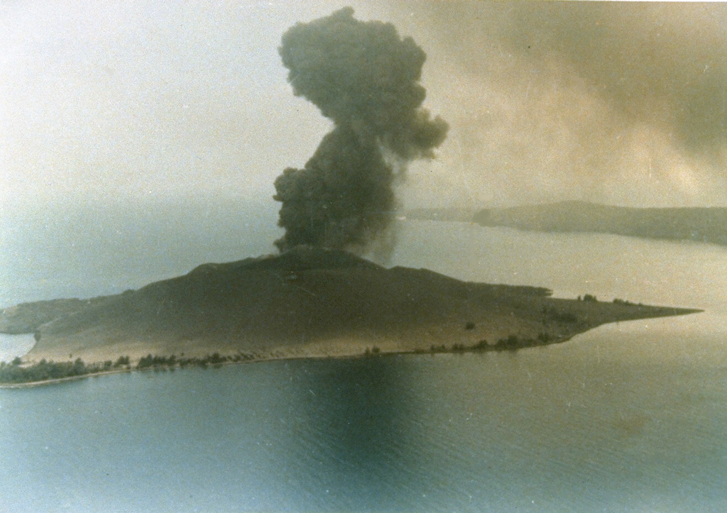 An explosive eruption in 1979 from Anak Krakatau is seen in an aerial view from the north. The island of Anak Krakatau, a post-caldera cone that has grown within the submarine caldera of 1883, first breached the surface in 1928. Photo by Adjat Sudradjat, 1979 (Volcanological Survey of Indonesia).