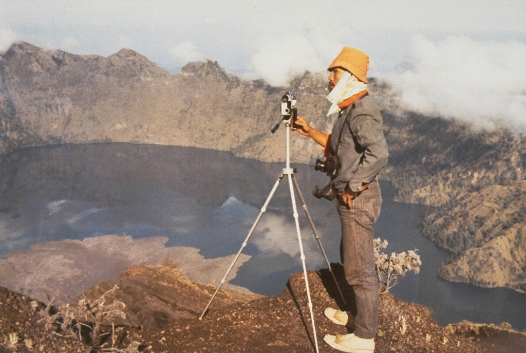 A scientist from the Volcanological Survey of Indonesia makes theodolite measurements along the N rim of the 5-km-wide Segara Anak caldera of Rinjani on Lombok Island. The lobate lava flow entering the lake at the lower left was erupted in 1944 from a vent on the NW flank of Gunung Barujari. Photo by Sumarna Hamidi, 1973 (Volcanological Survey of Indonesia).