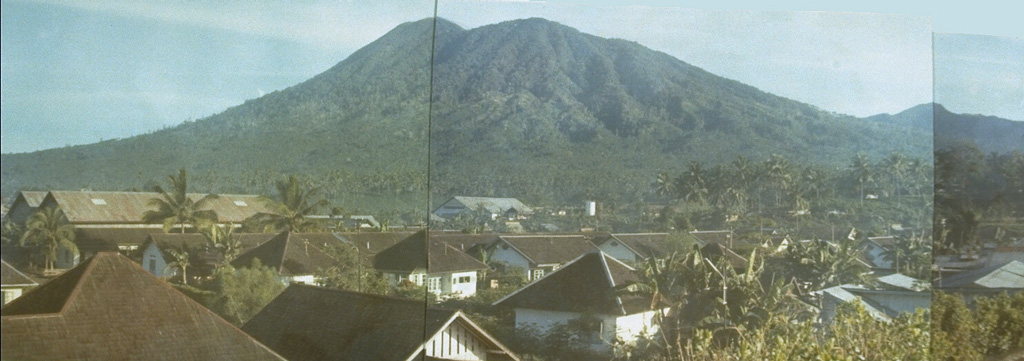 The 1149-m-high elongated Tongkoko volcano, seen in this composite photo from the south, rises above Bitung city and is the NE-most volcano on the island of Sulawesi.  The summit of the volcano, which is elongated in a NW-SE direction, contains a large crater with a central cone.  Historical eruptions have occurred since 1680 from both the summit and an east flank vent, Batu Angus.  Tongkoko volcano and its neighbor Dua Saudara are the most prominent features of Gunung Dua Saudara National Park, a noted wildlife preserve. Photo by A.R. Sumailani, 1973 (Volcanological Survey of Indonesia).