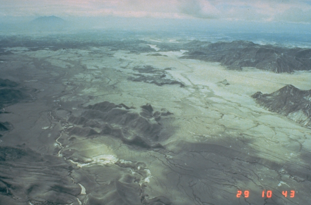 The broad light-colored areas are thick pyroclastic flow deposits from the 15 June 1991 Pinatubo eruption. This 29 June photo taken two weeks after the eruption is looking towards the east with Clark Air Base just beyond the margin of the pyroclastic flow fan. Debris flows or lahars have remobilized significant volumes of the unconsolidated pumice and ash since 1991. Mount Arayat is visible at the upper left. Photo by Ed Wolfe, 1991 (U.S. Geological Survey).