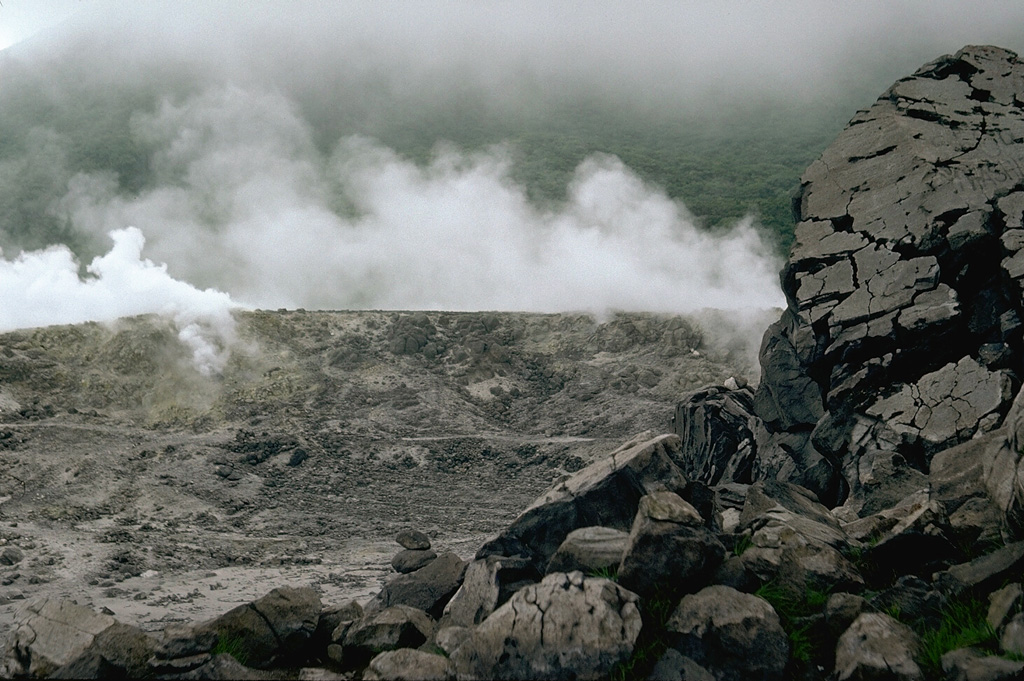 Plumes rise from Iwoyama ("Sulfur Mountain"), one of the largest thermal areas of the Kirishima volcano group. The Iwoyama thermal area is located between Karakunidake stratovolcano and Rokannon-Miike maar in the NW part of the volcanic field. Photo by Lee Siebert, 1988 (Smithsonian Institution).