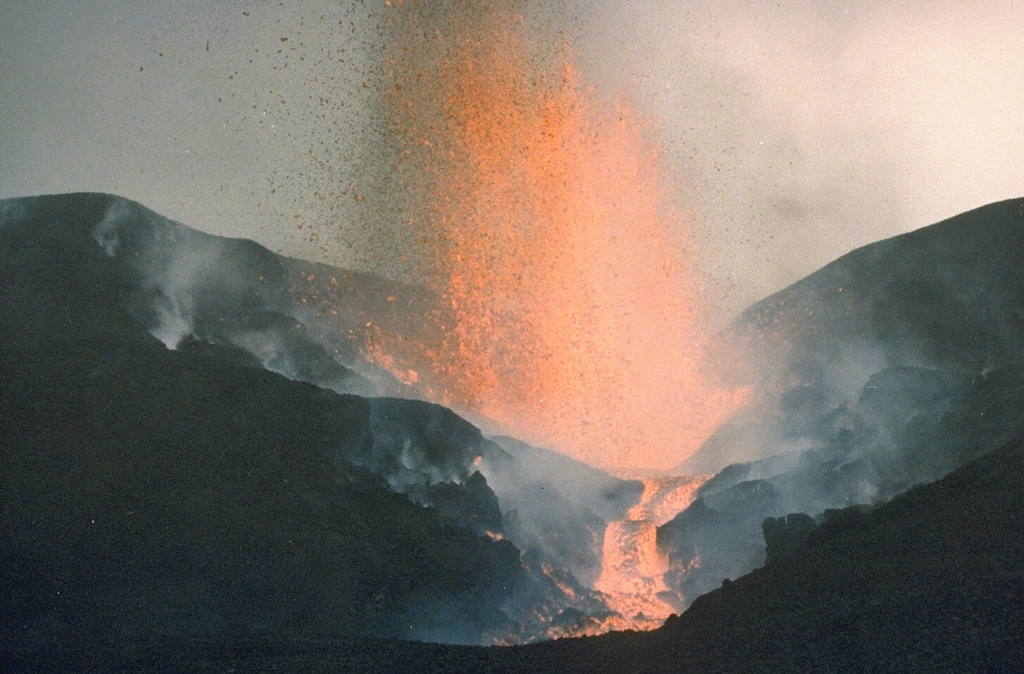 An eruption from a SSW-flank fissure 16 July to 20 August 1986, produced the Kitazungurwa scoria cone and a lava flow that traveled 19 km down the SW flank. The lava flow partially covered the SW-flank lavas from the 1976-77 Murara eruption. On 18 August the eruption changed from continuous lava fountaining to Strombolian activity. Crops were destroyed by hot ejecta and 150 cattle died from ingestion of ash-covered vegetation. Photo by D. Meurhaeghe, 1986.