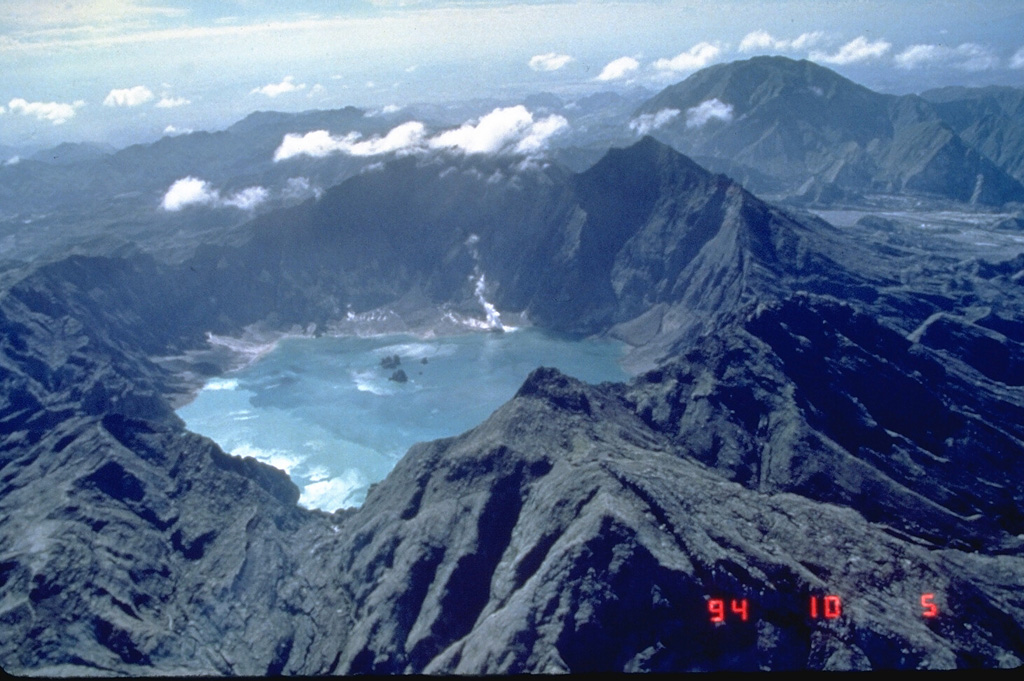 The 1991 eruption of Pinatubo in the Philippines created a new caldera with an average diameter of 2.5 km. Caldera collapse occurred following the ejection of around 5 km3 of material in one of the world's largest eruptions of the 20th century and lowered the height of the volcano by about 300 m. This 1994 view from the NW shows a lake within the caldera and two small islands from a partially submerged lava dome that was erupted in 1992. Photo by Ray Punungbayan, 1994 (Philippine Institute of Volcanology and Seismology).