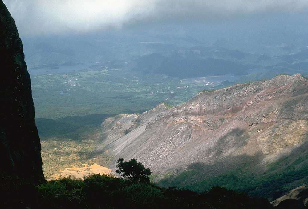 The steep topography at the right is the eastern rim of a scarp created by the 1888 collapse of Koandaisan, one of a group of cones forming Bandaisan. The two lakes in the distance, Onogawa (left) and Akimoto (right), formed after the resulting debris avalanche blocked river drainages. The caldera walls expose  stratigraphy of pyroclastic deposits overlain by lava flows. Photo by Lee Siebert, 1988 (Smithsonian Institution).