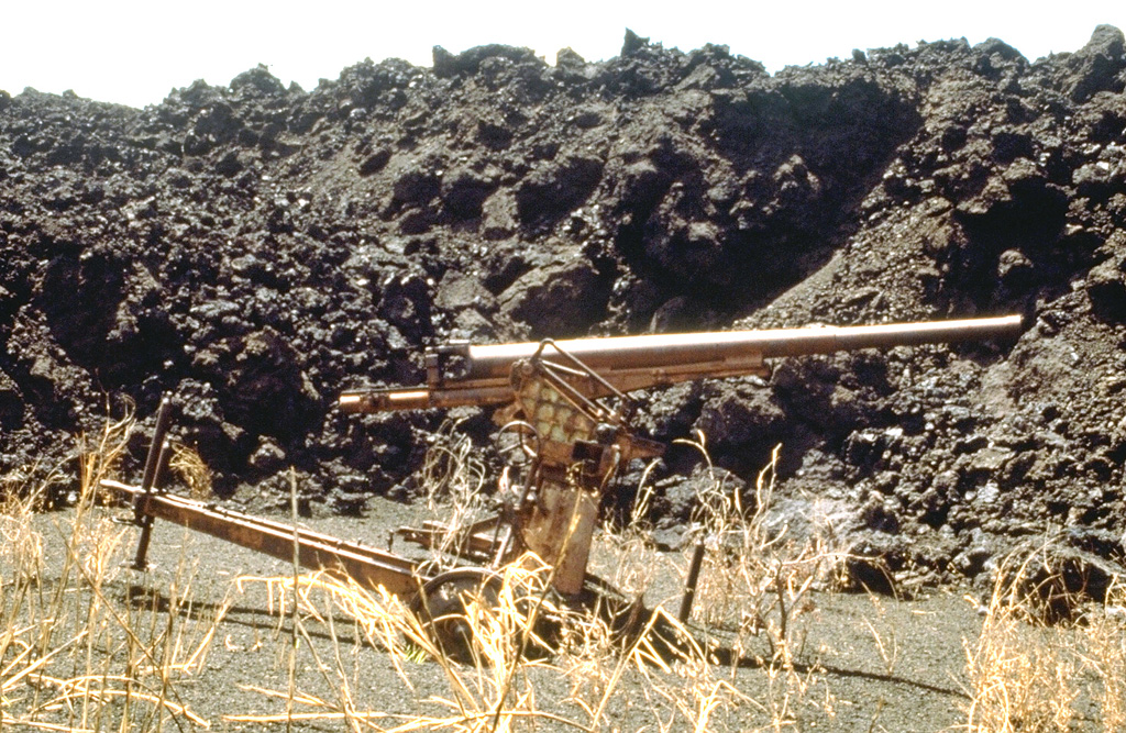 The SW-flank lava flow from the May 1981 eruption overran a Japanese World War II bunker and ashfall from the eruption partially buried this anti-aircraft gun. The lava flow traveled 3 km from its vent on the south crater rim. Other flows traveled down the north flank almost to the coast. Photo by Norm Banks, 1981 (U.S. Geological Survey).