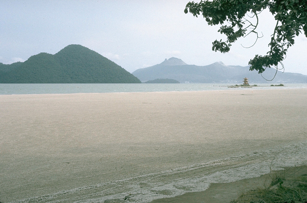 Usu rises at the right across Lake Toya with the Nakanojima lava dome complex at the left forming an island in the caldera lake. The light-colored area in the bottom half of this 12 August 1977 photo is floating pumice produced by explosive eruptions of Usu during 7-9 August. Photo by Lee Siebert, 1977 (Smithsonian Institution).