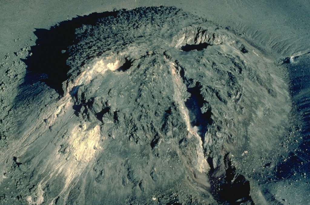 This face-like feature is formed by fissures cutting across a lava dome at the summit of Tarumai volcano on the northern Japanese island of Hokkaido.  Two sets of fissures transect the dome, the one trending N30W (lower right) forming the "nose," and the other trending N60E.  The lava dome dates to an eruption in 1909.  The N60E fissure was formed during an eruption in 1917; later localized eruptions formed the "eyes."  Copyrighted photo by Katia and Maurice Krafft, 1981.