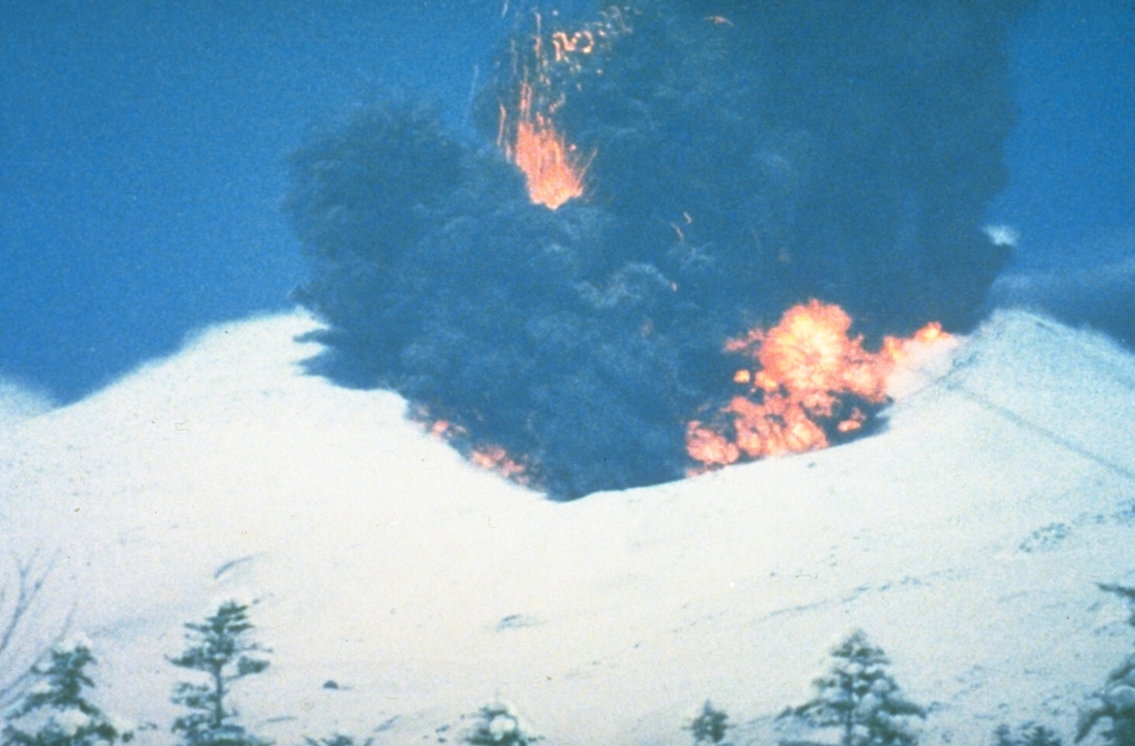 A phreatomagmatic explosion on 25 December 1988 at Japan's Tokachi volcano ejects incandescent blocks and a dark ash cloud. At the base of the ash plume is the leading edge of a small pyroclastic surge that eventually traveled down the N flank to 1 km from the vent. The 1988 eruption began with a phreatic explosion on 16 December. Intermittent explosive eruptions with small pyroclastic flows and surges began on 19 December and continued until 5 March 1989. Photo courtesy of Japan Meteorological Agency, 1988.