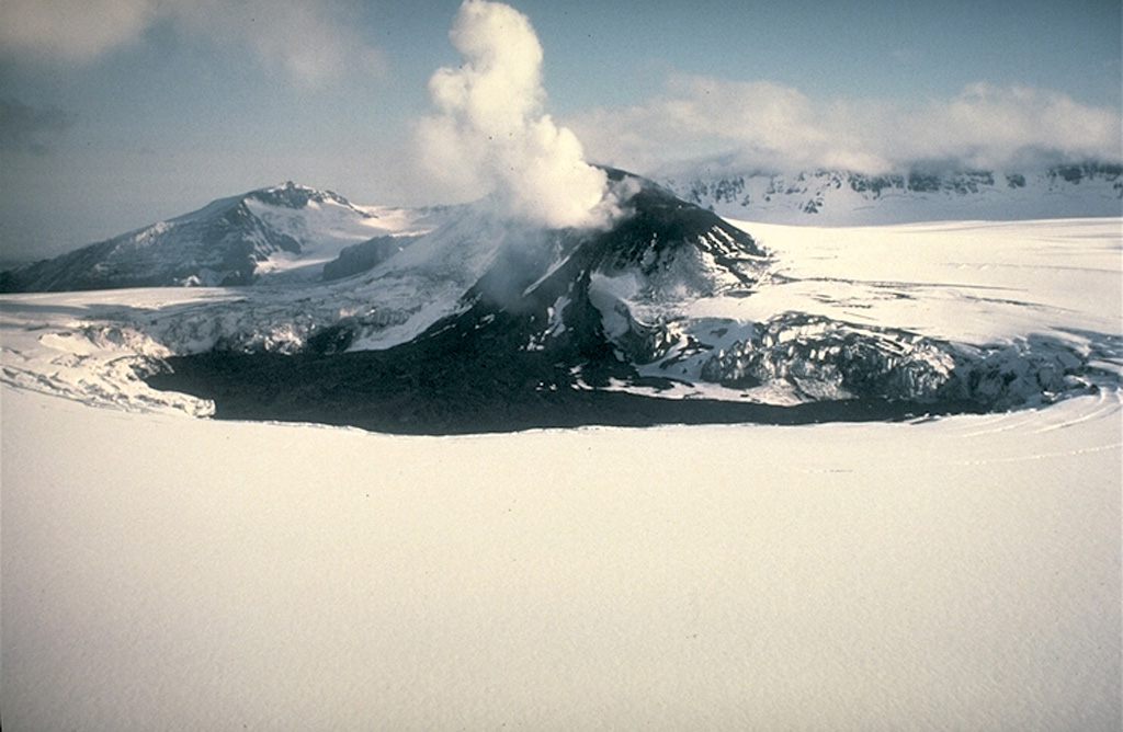 A scoria cone on the Veniaminof western summit caldera floor was the source of the dark lava flow that melted through glacial ice. This photo was taken from the SE on 15 June 1984, two months after the eruption ended, and shows the rim of the 8 x 11 km wide caldera in the background. The caldera rim contains Cone Glacier on the west side (to the far left) and is overtopped by glaciers on the south and SE sides. Photo by Alaska Volcano Observatory, U.S. Geological Survey, 1984.