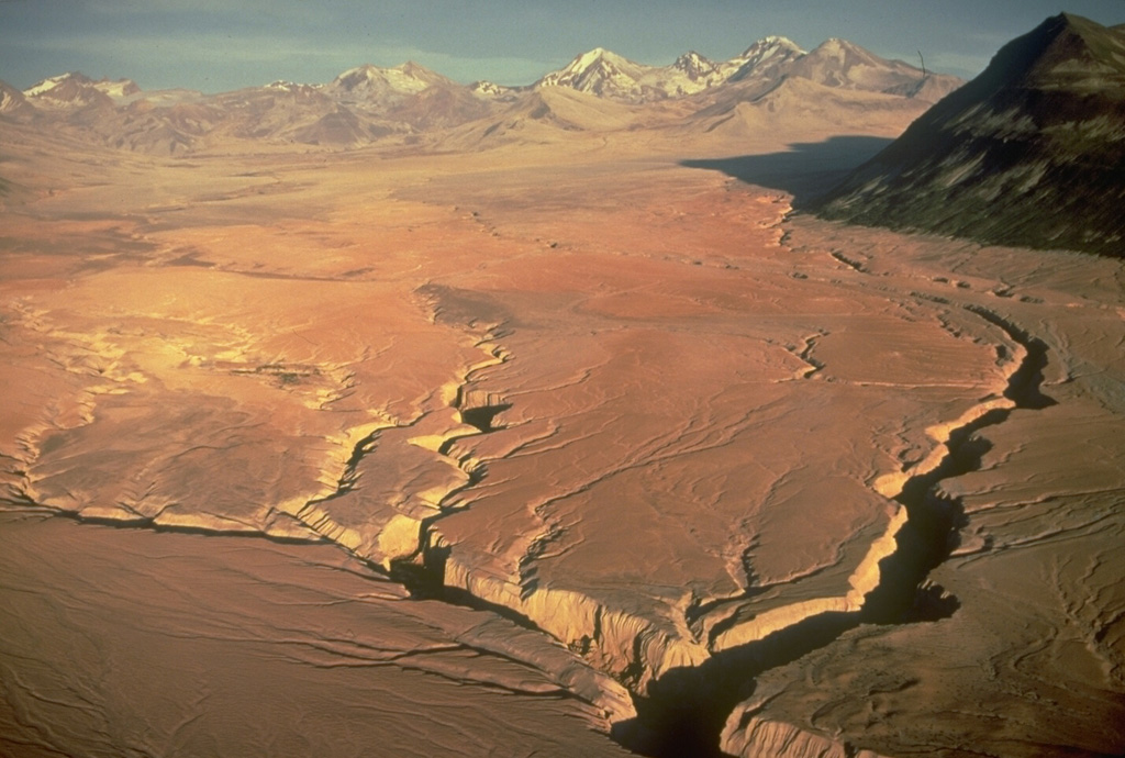 This entire valley floor consists of deposits of the Valley of Ten Thousand Smokes (VTTS) ash flow, which was erupted from Alaska's Novarupta volcano, out of view to the left.  The massive, 11-15 cu km VTTS ash-flow covers 120 km2 of the valley to a distance of 12 km from the Novarupta vent.  The bowl-shaped portion of the left-half skyline is the rim of Katmai caldera, which collapsed as a result of the eruption of the VTTS ash flow.  The four skyline peaks on the right side of this aerial view from the NW are those of Trident volcano. Copyrighted photo by Katia and Maurice Krafft, 1978.
