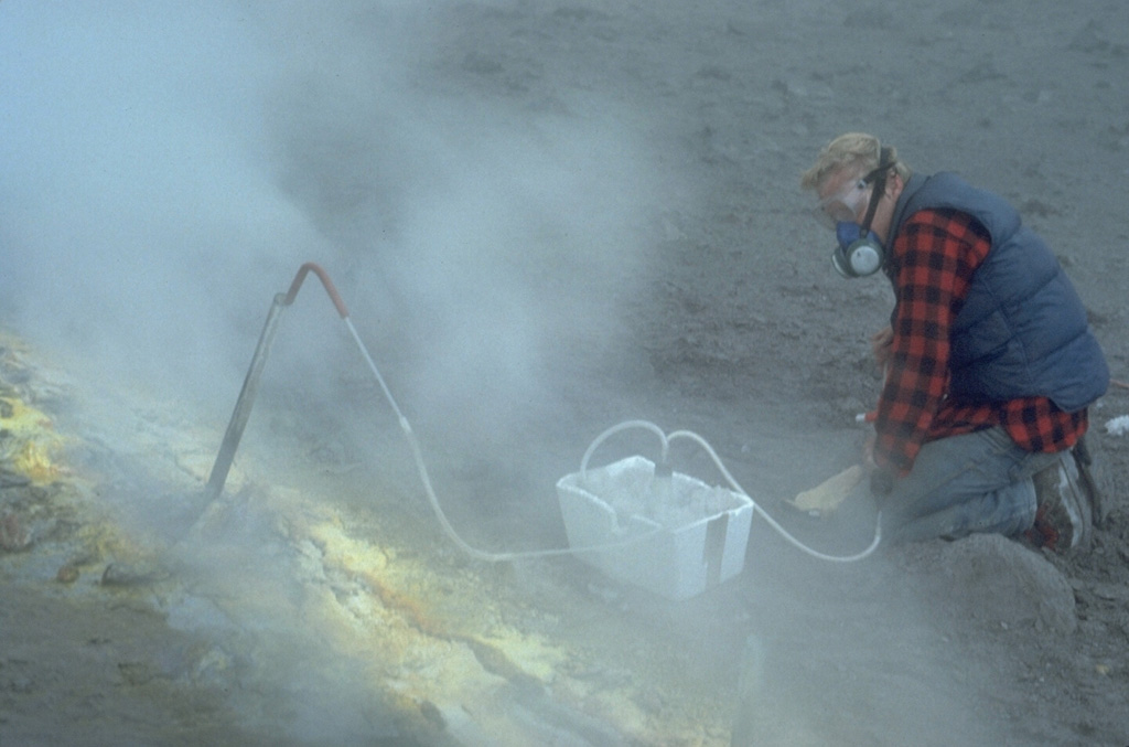 A volcanologist takes gas samples from a sulfur-encrusted fumarole at the summit of Augustine during a quiescent period of the 1986 eruption. Fumarole condensates had a pH of between 0 and 0.5. The maximum measured gas temperatures were 625-645°C. Photo by Lee Siebert, 1986 (Smithsonian Institution).