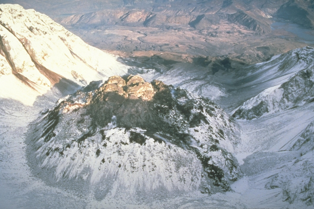 This view from above the south rim of the crater of Mount St. Helens shows the lava dome partially filling the crater on 28 October 1986, at the very end of the 1980-86 eruption. After six years of episodic growth the lava dome reached a height of 250 m and a diameter of 1,100 m. Photo by Lyn Topinka, 1986 (U.S. Geological Survey).