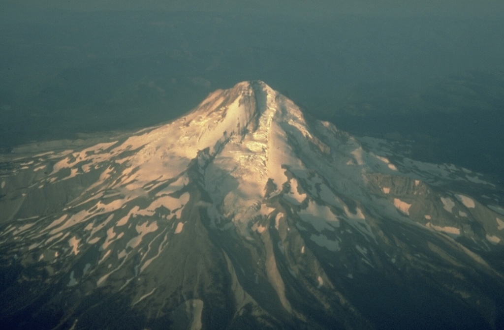This aerial view from the NE shows Eliot Glacier descending the valley in the center, with glacial moraines at its base. During the late Pleistocene a major lahar from Mount Hood swept to the north across the Columbia River, temporarily filling it to a depth of 30 m. Photo by Richard Waitt, 1983 (U.S. Geological Survey).