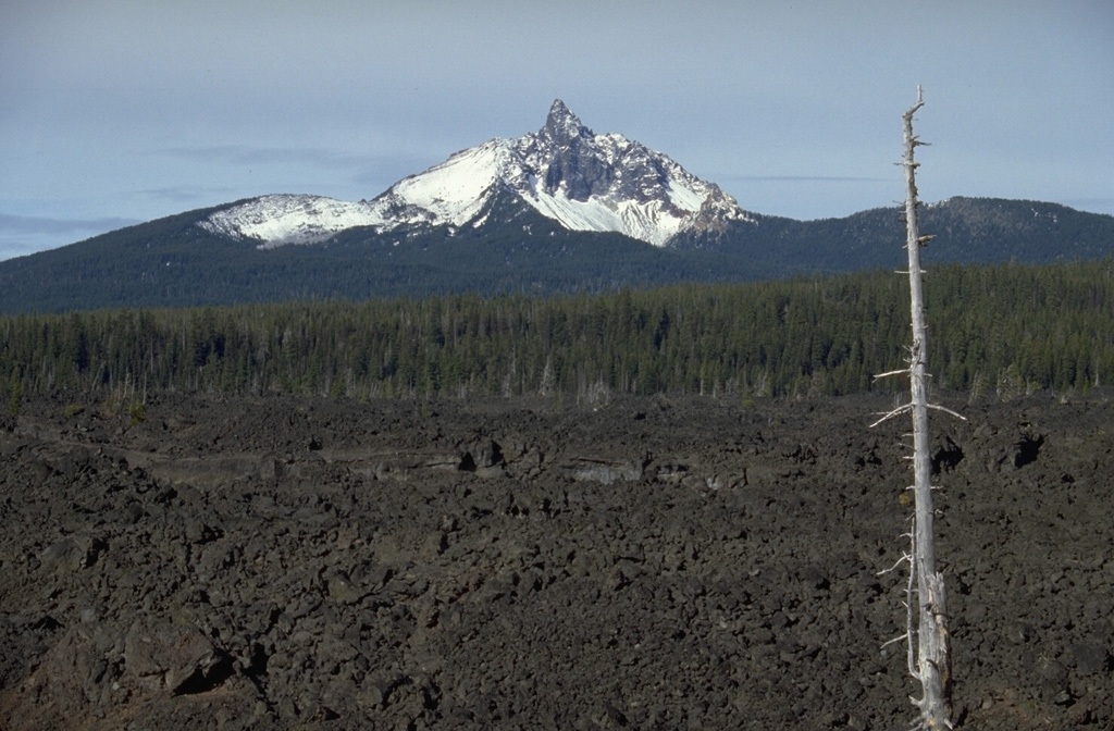 The dramatic summit pinnacle of Mount Washington is a central lava plug that caps a shield volcano.  Mount Washington has been extensively dissected by glacial erosion, revealing the inner structure of the volcano.  Fresh lava flows from cinder cones near North Sister volcano appear in the foreground of this view from the SE. Photo by Lee Siebert, 1995 (Smithsonian Institution).