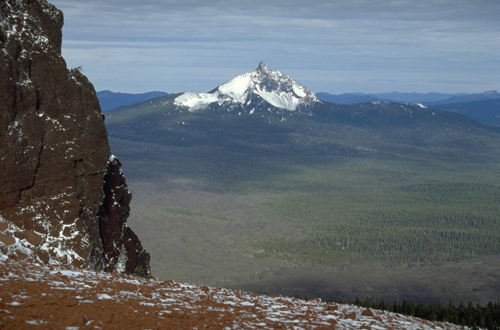 Mount Washington, seen here from Black Butte to the SE, is an eroded Pleistocene shield volcano capped by a steep central lava plug.  NE flank spatter cones were active about 1300 years ago.  Fresh lava flows in the foreground of this photo originated from Belknap volcano and cinder cones near North Sister volcano. Photo by Lee Siebert, 1995 (Smithsonian Institution).