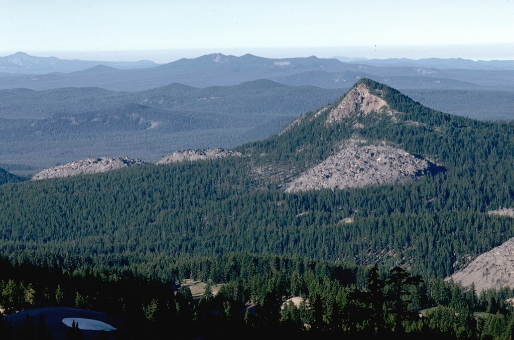 The center of the Devils Hill chain on the SE flank of South Sister contains several small lava domes and flows that are more widely spaced than those at the northern and southern ends. The flows are named for Devils Hill, the partially forested peak to the right. Photo by Lee Siebert, 1982 (Smithsonian Institution).