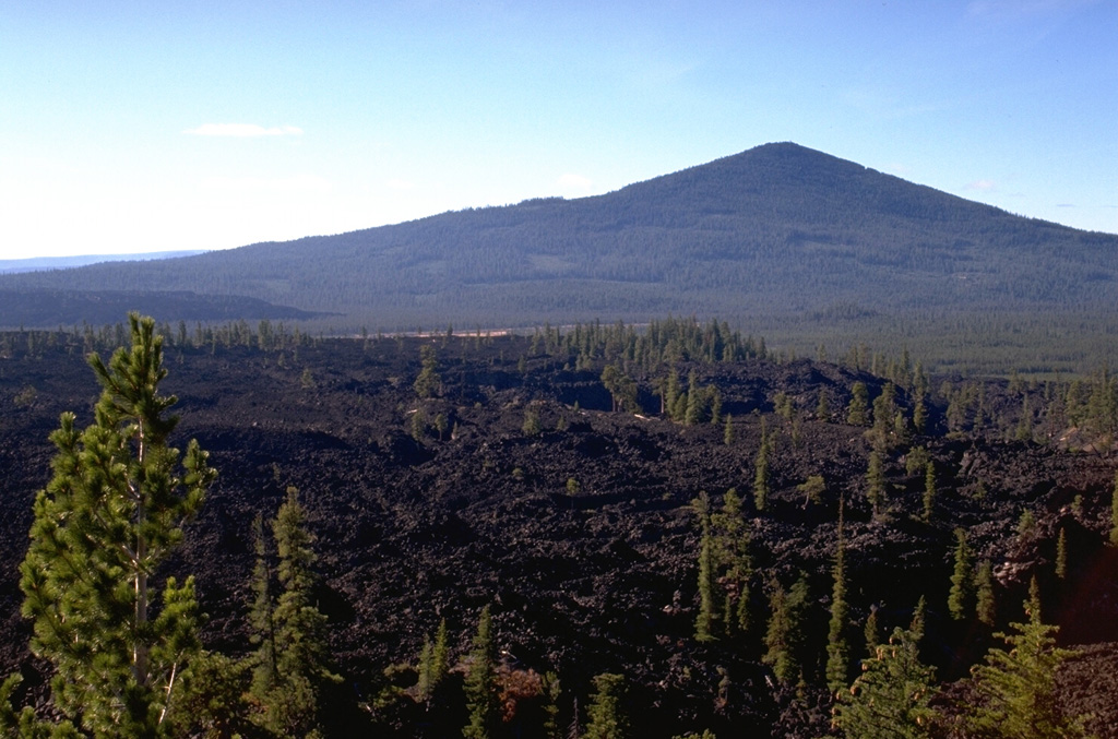 The middle of three andesite lava flows that erupted from three vents near Davis Lake has been radiocarbon dated at 5,050-5,600 years. The Pleistocene Odell Butte shield volcano is in the background, and the southernmost of the three lava flows can be seen in the distance below its left flank. Photo by Lee Siebert, 1995 (Smithsonian Institution).