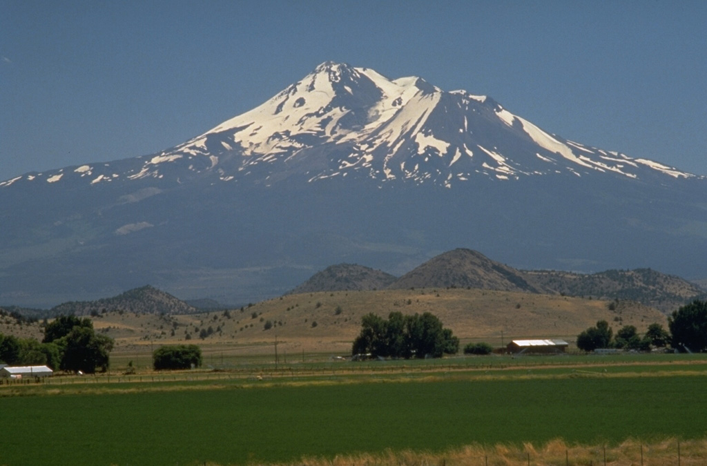 The foreground hills are part of the Shasta Valley debris avalanche deposit produced by one of the largest known Quaternary volcanic landslides. Roughly 46 km3 of an ancestral Mount Shasta collapsed about 350,000 year ago, producing a massive debris avalanche that swept some 50 km to the north, filling the broad Shasta Valley with hummocky debris. Photo by Dave Wieprecht, 1995 (U.S. Geological Survey).