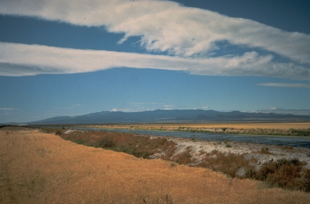 The massive Medicine Lake volcano in NE California, seen here from the NE, encompasses a 50 x 80 km wide area. Holocene eruptions included obsidian flows from summit and flank vents, and voluminous basaltic lava flows from vents on the north and south flanks. Recent eruptions took place about 900 years ago. The summit area includes a 7 x 11 km caldera. Photo by Julie Donnely-Nolan, 1982 (U.S. Geological Survey).