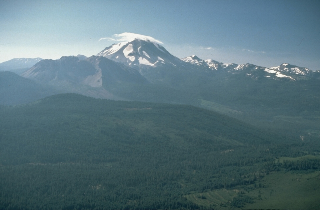 An aerial view of cloud-capped Lassen Peak from the NW shows the Chaos Crags lava dome complex on its left, the source of rockfall avalanche in 1650 CE, and the older Brokeoff stratovolcano and post-caldera lava domes on the right.  Lassen Peak was the source of California's latest eruption, that lasted from 1914 to 1917. Photo by Lyn Topinka, 1984 (U.S. Geological Survey).