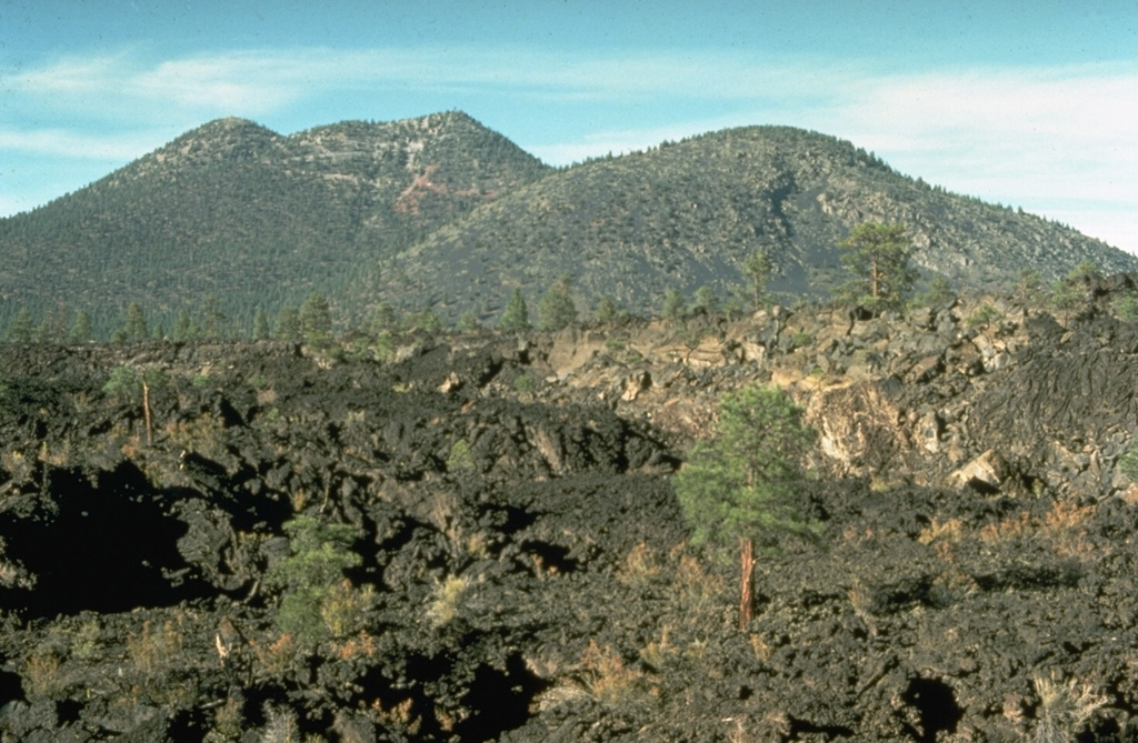 The rugged Bonito lava flow in the foreground was erupted from Sunset Crater in two stages.  The flow originated from vents at the west to NW base of Sunset Crater, which is out of view to the right.  The peak beyond the flow to the north is O'Leary Peak, which consists of two rhyodacitic lava domes of Pleistocene age.  O'Leary Peak is the NE-most silicic center in the San Francisco Mountain volcanic field. Photo by Richard Moore, 1975 (U.S. Geological Survey).