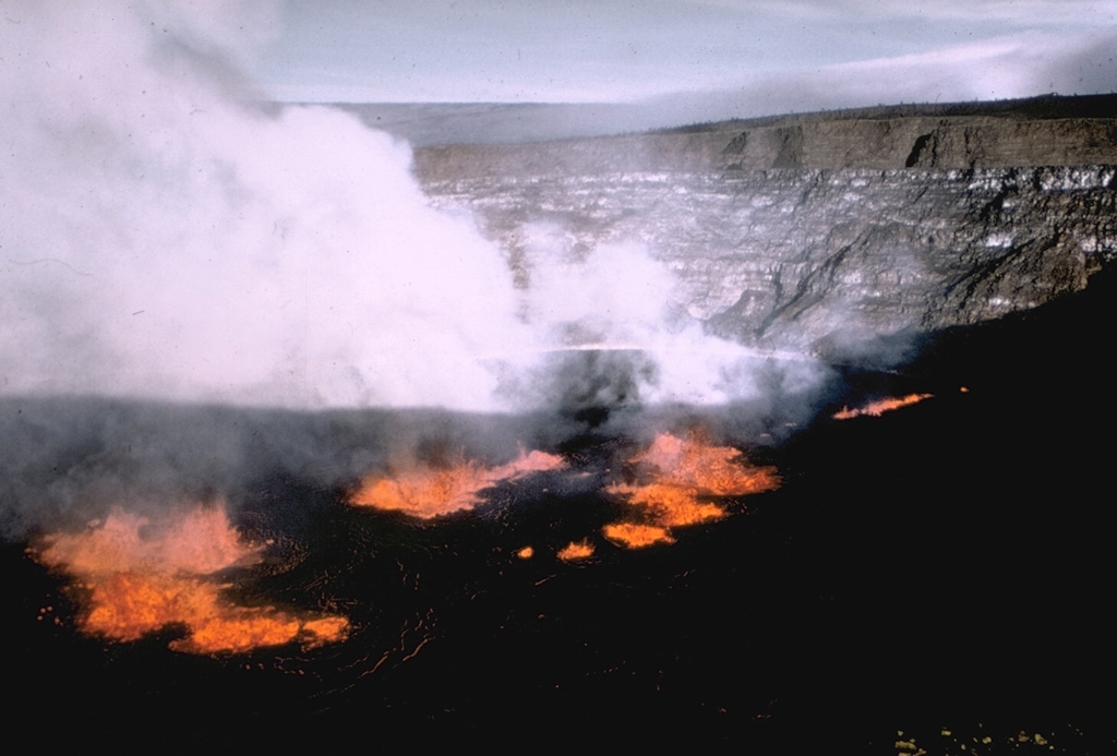 A lava lake formed within Halema‘uma‘u crater on 5 November 1967. In the background of this view from the SE can be seen thin, light-colored lava flows exposed in the crater walls, with the Kilauea caldera wall above it, and the flank of Mauna Loa in the distance. Lava lake activity continued until 13 July 1968. Photo by U.S. Geological Survey, 1967.